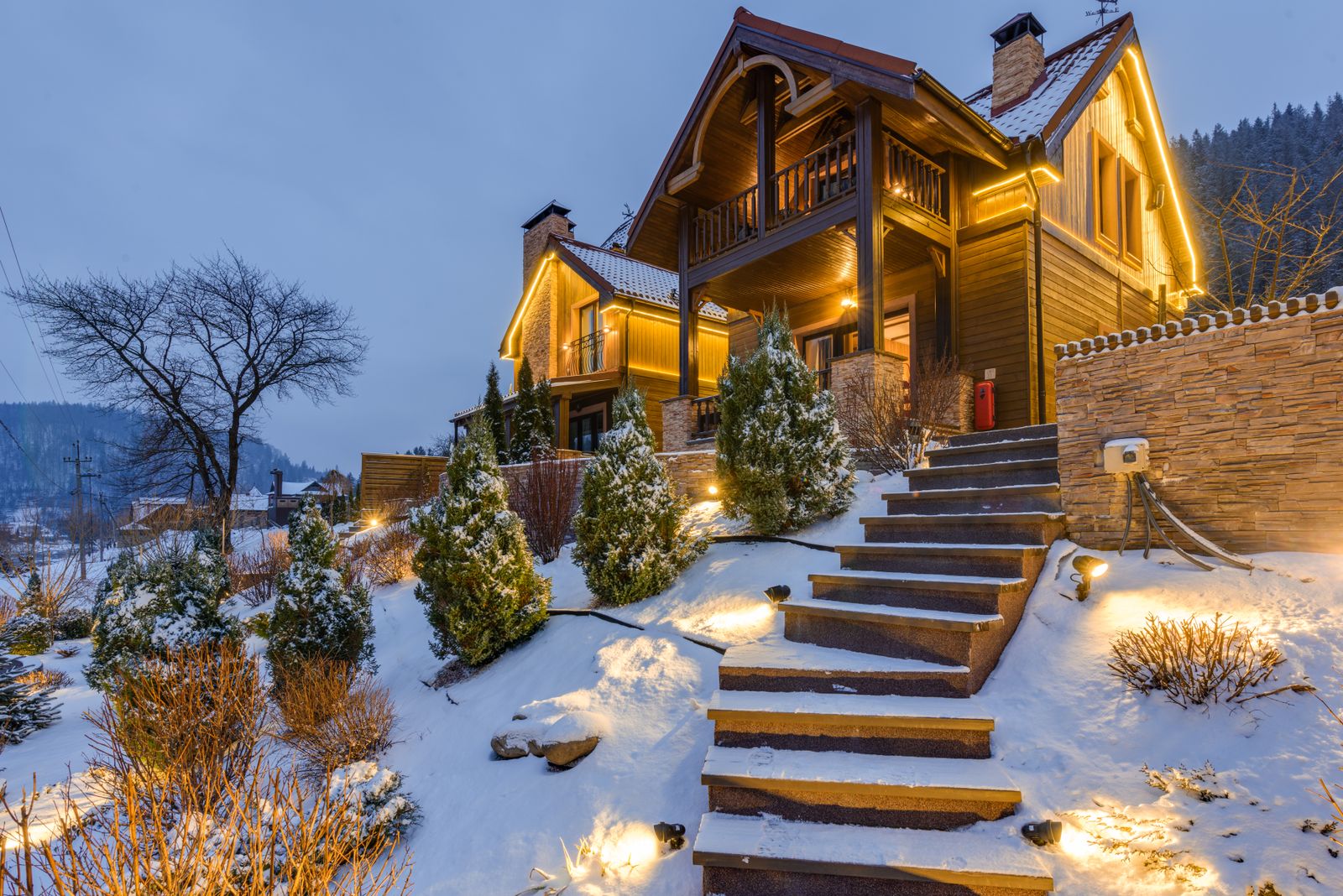 Pinecrest Mountain Lodge at blue hour, timber gables warmly lit above a snow-covered slope of pines